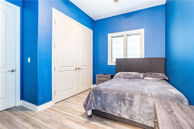 bedroom featuring a closet, light wood-style flooring, and baseboards