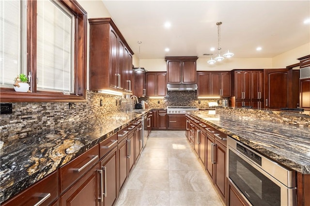 kitchen with dark stone counters, hanging light fixtures, and tasteful backsplash