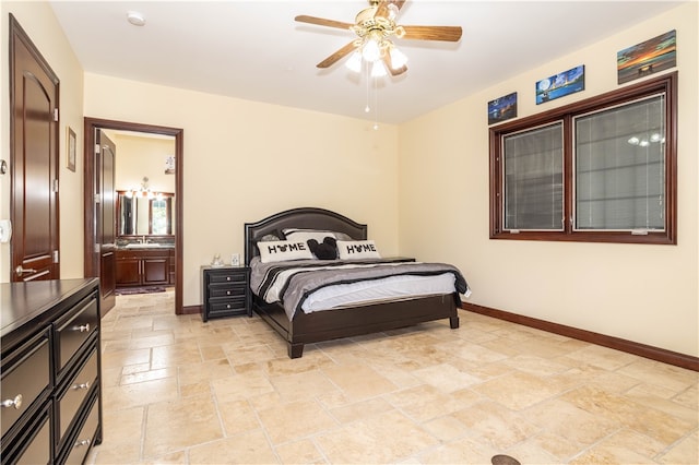 bedroom featuring ensuite bath, stone tile floors, baseboards, and a ceiling fan