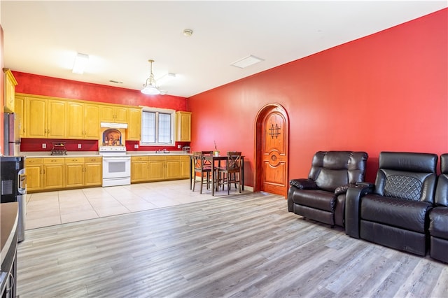 kitchen featuring a sink, open floor plan, light countertops, light wood-type flooring, and white range with electric cooktop