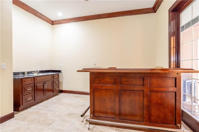 interior space featuring ornamental molding, light tile patterned flooring, a sink, and baseboards