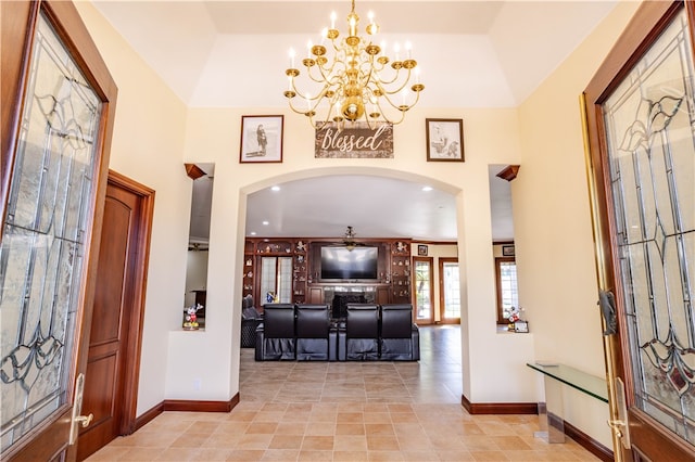 foyer featuring arched walkways, a notable chandelier, a towering ceiling, and baseboards