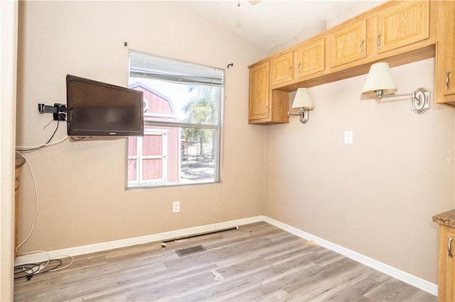 kitchen featuring light brown cabinetry, light wood-style floors, light countertops, and baseboards