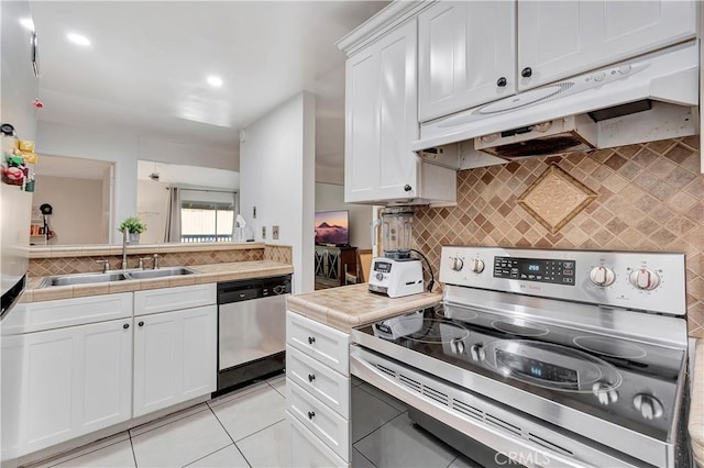 kitchen featuring decorative backsplash, stainless steel appliances, sink, light tile patterned floors, and white cabinetry