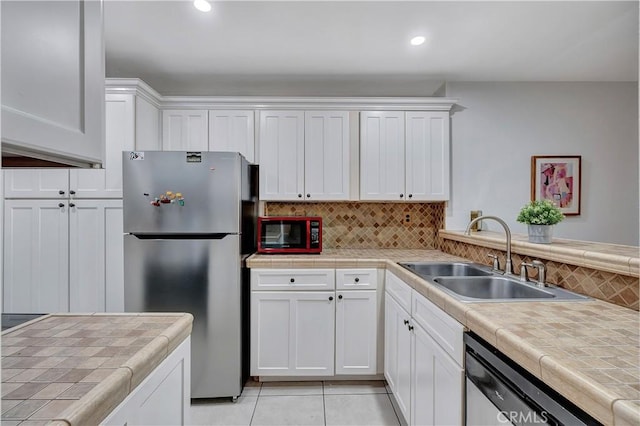 kitchen featuring tile counters, white cabinets, stainless steel appliances, and sink