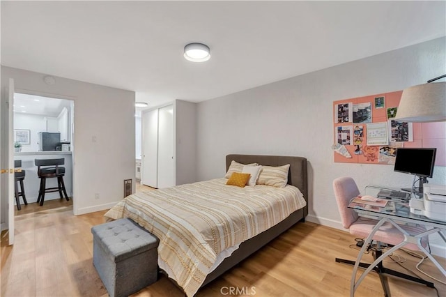 bedroom with stainless steel fridge and light wood-type flooring