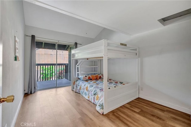 bedroom featuring hardwood / wood-style floors, access to outside, and vaulted ceiling