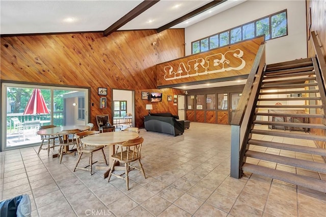 tiled dining room with beam ceiling, a wealth of natural light, wooden walls, and high vaulted ceiling