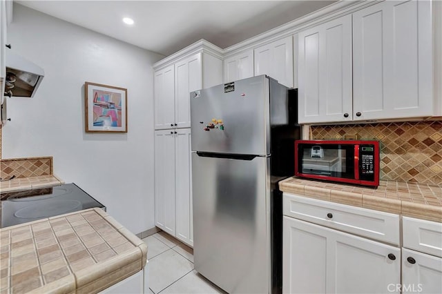 kitchen featuring decorative backsplash, appliances with stainless steel finishes, extractor fan, tile countertops, and white cabinets