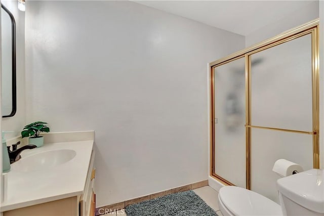 bathroom featuring toilet, vanity, tile patterned floors, and a shower with shower door