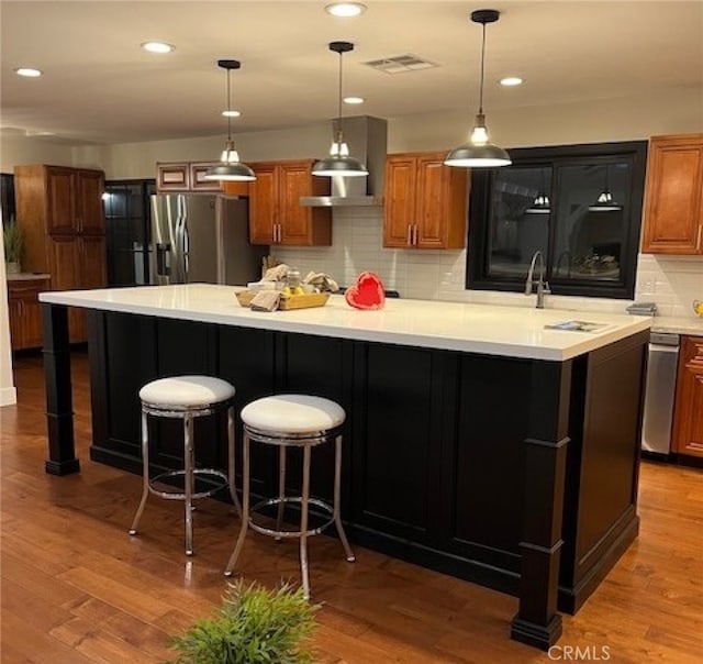 kitchen featuring a breakfast bar, backsplash, a spacious island, stainless steel refrigerator with ice dispenser, and wood-type flooring