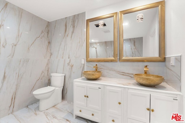 bathroom with vanity, toilet, and tile walls