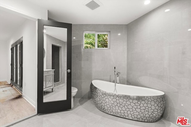 bathroom featuring tile walls, toilet, and a bathing tub