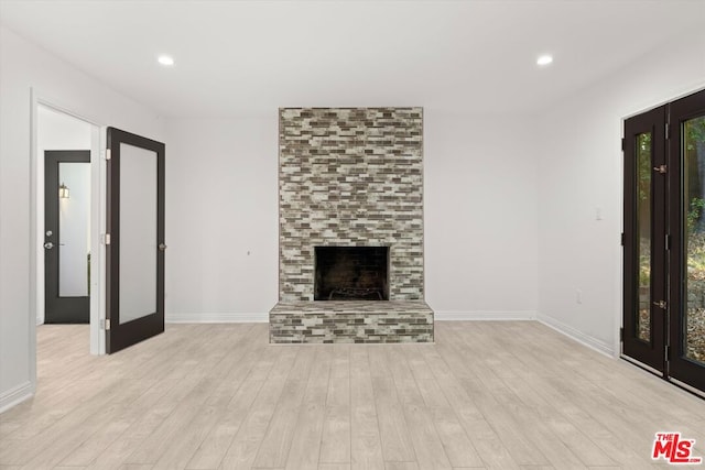 unfurnished living room with light hardwood / wood-style flooring, plenty of natural light, and a fireplace