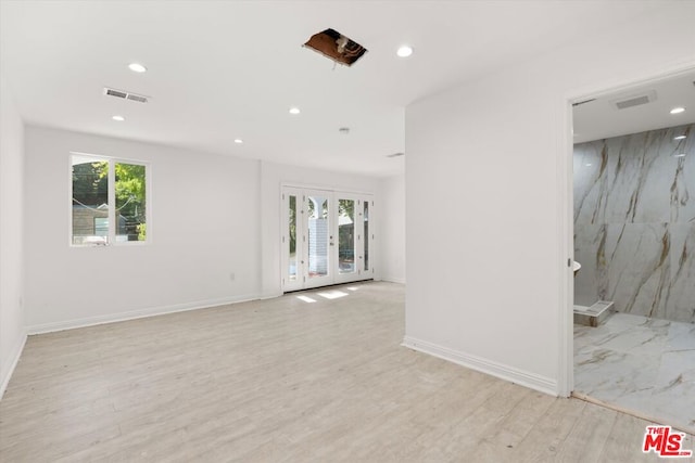 unfurnished room featuring french doors, light hardwood / wood-style floors, and a healthy amount of sunlight