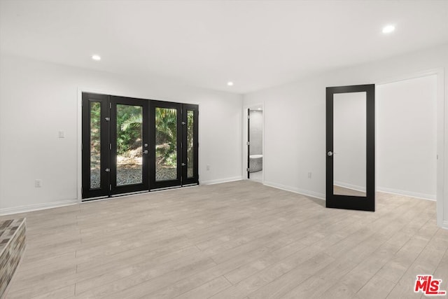 empty room featuring french doors and light hardwood / wood-style flooring