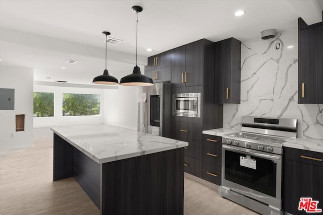 kitchen with appliances with stainless steel finishes, a kitchen island, hanging light fixtures, decorative backsplash, and light hardwood / wood-style flooring