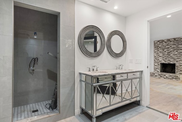 bathroom with vanity, a stone fireplace, and tiled shower