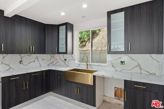 kitchen featuring light stone countertops, backsplash, beamed ceiling, and sink