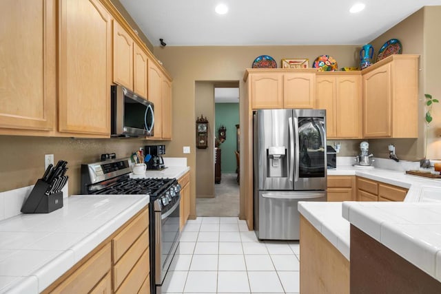 kitchen with tile counters, light tile patterned floors, light brown cabinets, and appliances with stainless steel finishes