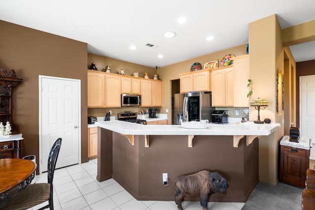 kitchen featuring tile counters, a kitchen breakfast bar, kitchen peninsula, and stainless steel appliances