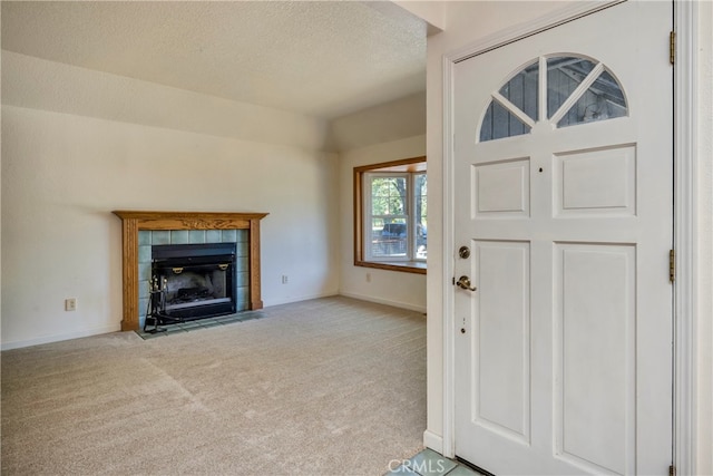 carpeted foyer entrance featuring a textured ceiling and a fireplace