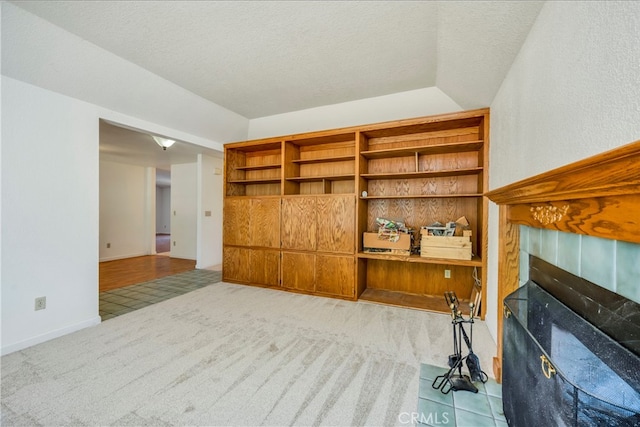 carpeted living room featuring a textured ceiling and a tile fireplace