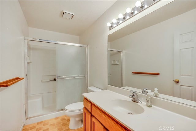 bathroom featuring a shower with door, vanity, and toilet