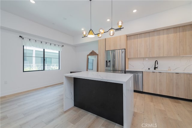 kitchen with sink, hanging light fixtures, stainless steel appliances, light stone countertops, and decorative backsplash