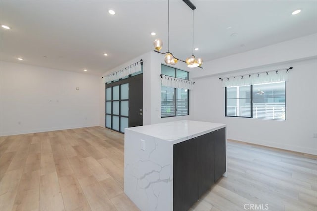 kitchen featuring light stone counters, a barn door, decorative light fixtures, and light hardwood / wood-style flooring