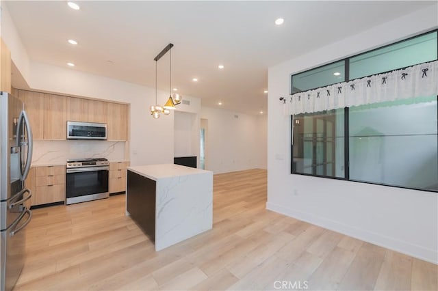 kitchen featuring appliances with stainless steel finishes, tasteful backsplash, hanging light fixtures, light brown cabinets, and light wood-type flooring