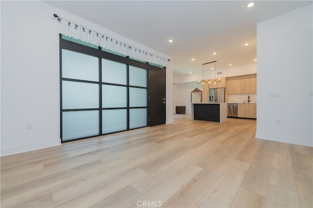 unfurnished living room with a barn door and light hardwood / wood-style flooring