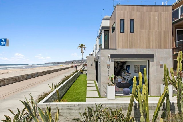 back of house with a water view and a view of the beach