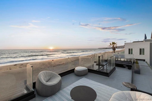 patio terrace at dusk with a water view and a beach view