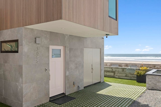 view of outdoor structure featuring a water view and a beach view