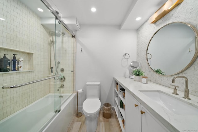 full bathroom with shower / bath combination with glass door, vanity, hardwood / wood-style flooring, and toilet