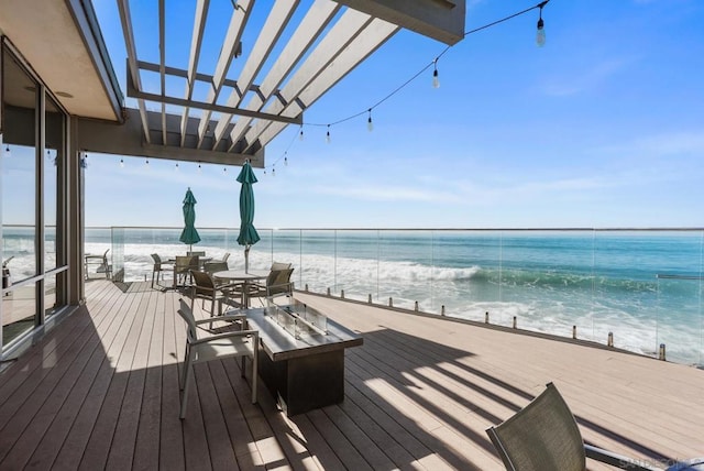 wooden terrace featuring a view of the beach and a water view