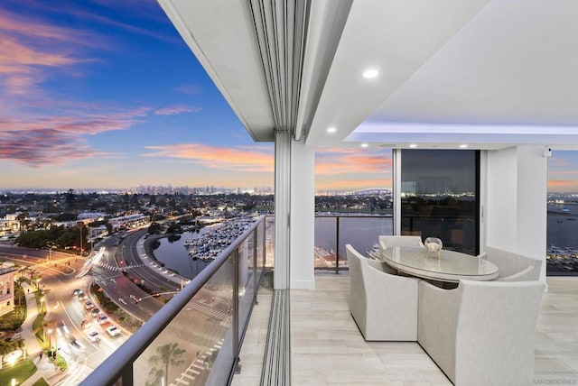 balcony at dusk featuring a water view