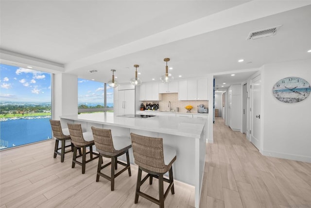 kitchen featuring white cabinets, decorative light fixtures, light hardwood / wood-style floors, and a large island