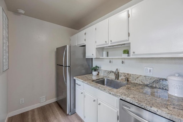 kitchen featuring sink, light hardwood / wood-style flooring, appliances with stainless steel finishes, light stone countertops, and white cabinets