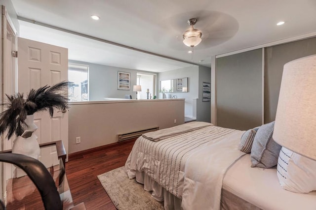 bedroom with multiple windows, ceiling fan, dark hardwood / wood-style flooring, and baseboard heating