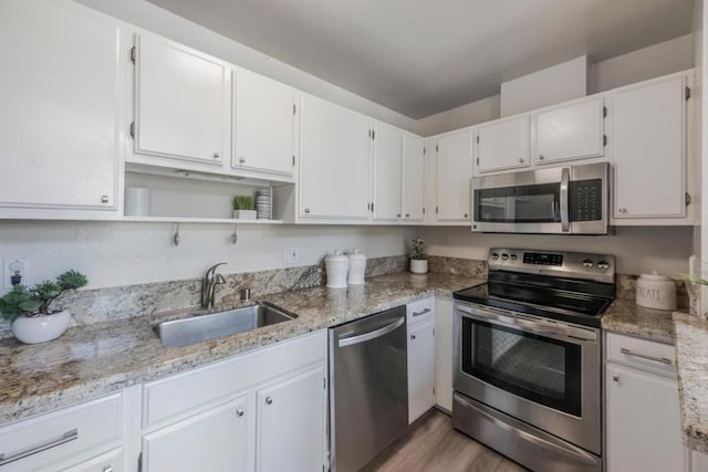 kitchen with light stone counters, appliances with stainless steel finishes, sink, and white cabinets