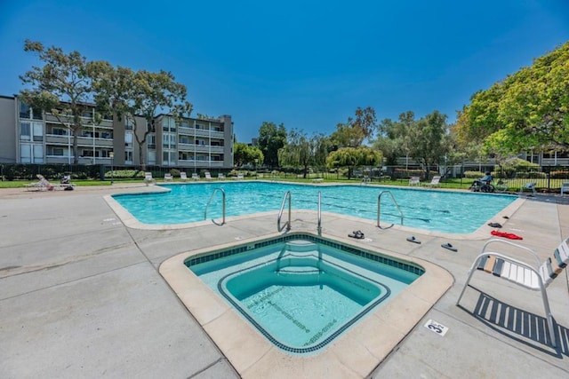 view of swimming pool featuring a hot tub and a patio area