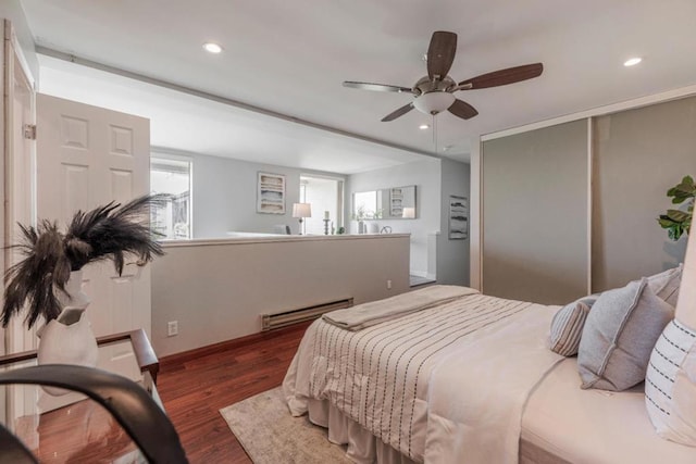 bedroom featuring a baseboard heating unit, dark wood-type flooring, and ceiling fan