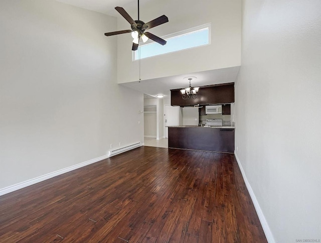 unfurnished living room featuring a towering ceiling, a baseboard radiator, ceiling fan with notable chandelier, and hardwood / wood-style flooring