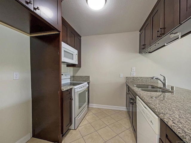 kitchen featuring dark brown cabinets, white appliances, sink, stone countertops, and light tile patterned flooring