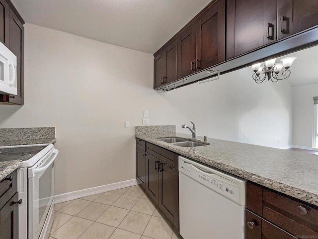 kitchen featuring dark brown cabinetry, sink, light tile patterned floors, and white appliances