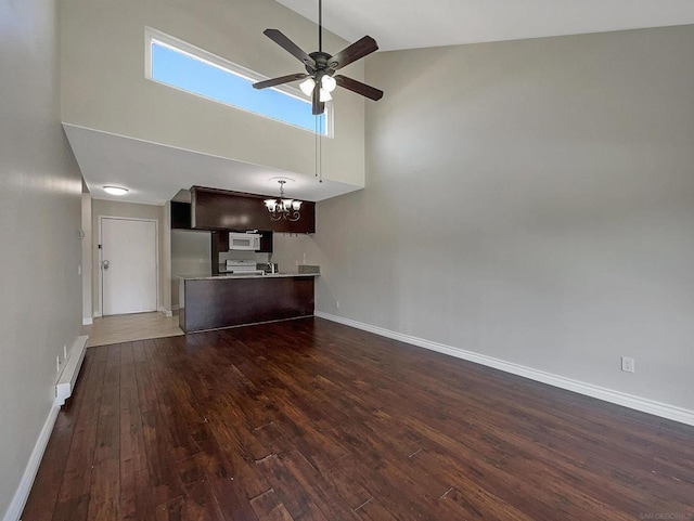 unfurnished living room featuring ceiling fan with notable chandelier, dark hardwood / wood-style floors, and high vaulted ceiling