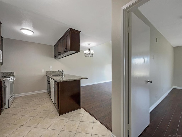 kitchen with dark brown cabinetry, sink, white electric range, light stone counters, and light wood-type flooring