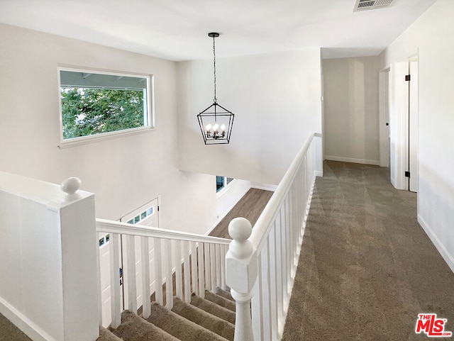 stairs with carpet and a chandelier